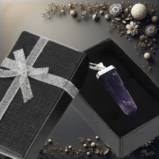 Amethyst crystal pendant in a black box with decorative elements on a dark surface