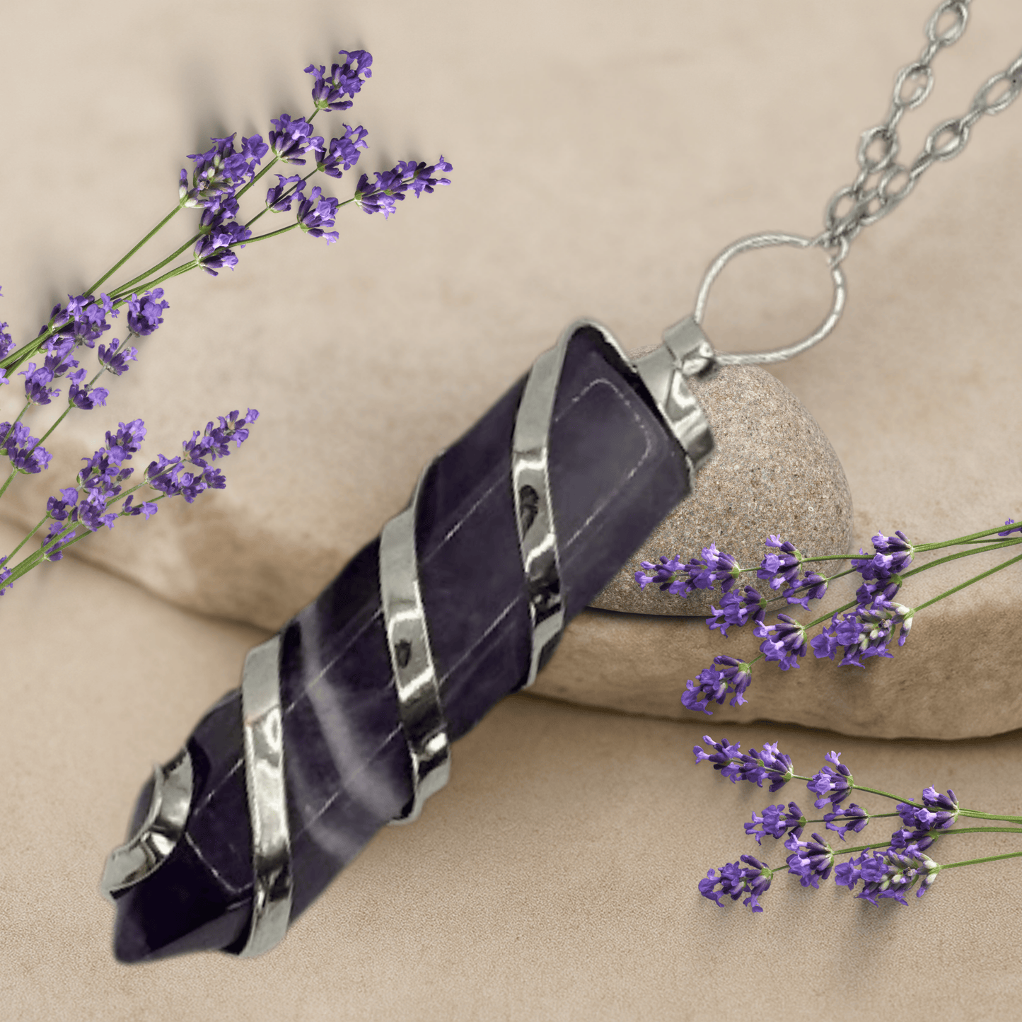 Amethyst crystal necklace with silver accents on a beige background with lavender flowers.