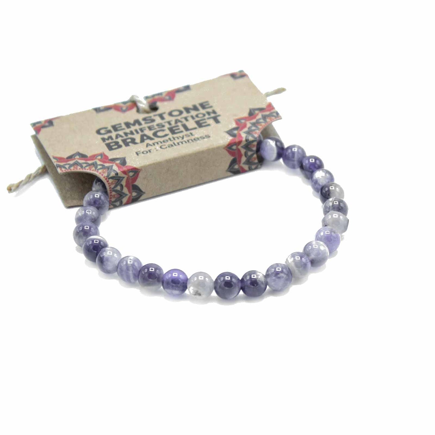 A beaded gemstone bracelet in shades of purple, lavender, and white, displayed on a kraft paper tag that reads 'GEMSTONE MANIFESTATION BRACELET Amethyst For Calmness.