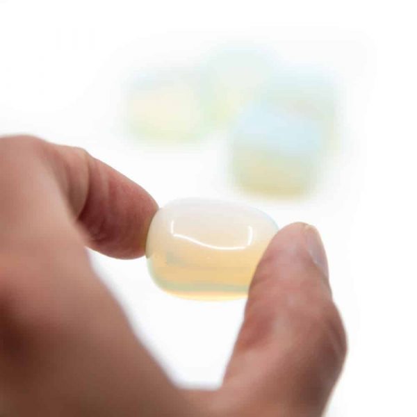 Opalite tumlestone being held between two fingers