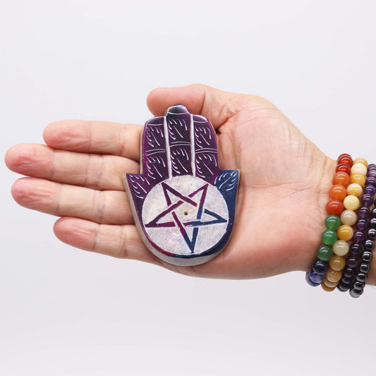 Hand holding a pentacle pendant with a white background