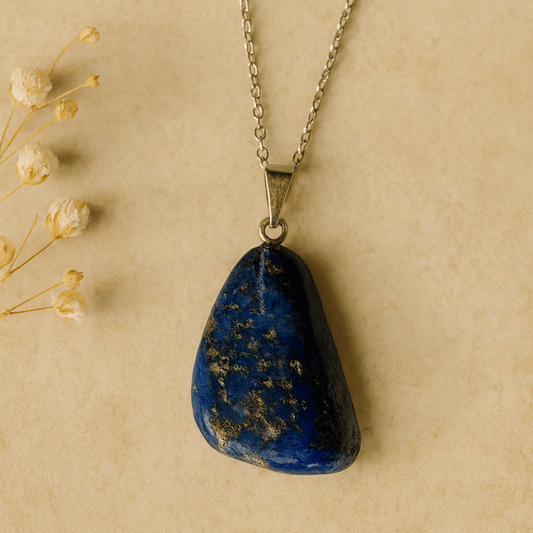 Blue stone pendant on a chain against a beige background with dried flowers.