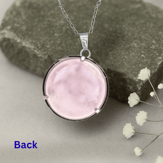 Necklace showin the back of the pink rose quartz pendant on a stone surface with flower