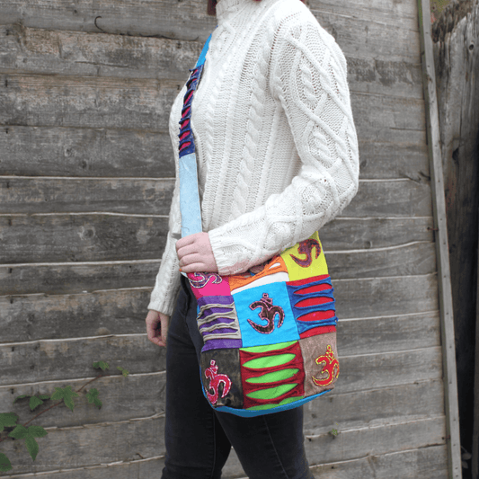 Person wearing a colorful patchwork bag against a wooden wall.