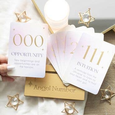 Set of angel number cards with gold accents on a wooden surface.