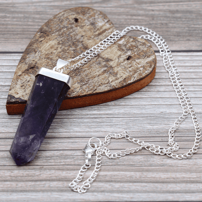 Necklace with a purple crystal pendant on a wooden surface