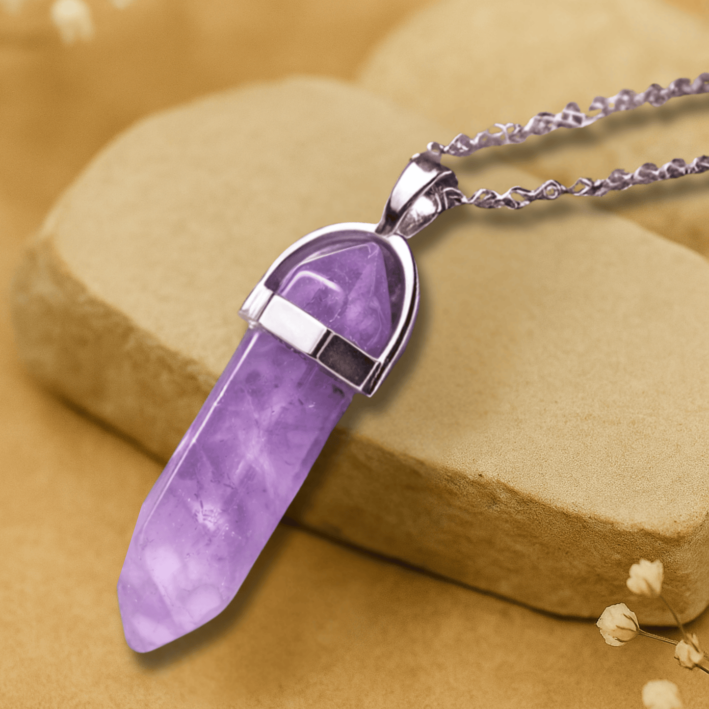 Amethyst purple point pendant with a horseshoe alloy silver holder  connecting  to a silver chain draped over brown slate