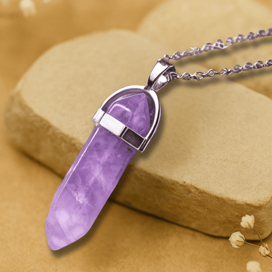 Amethyst purple point pendant with a horseshoe alloy silver holder  connecting  to a silver chain draped over brown slate
