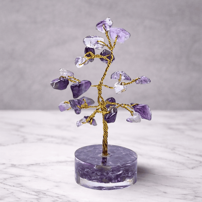 Crystal tree with purple and clear stones on a marble base against a gray background