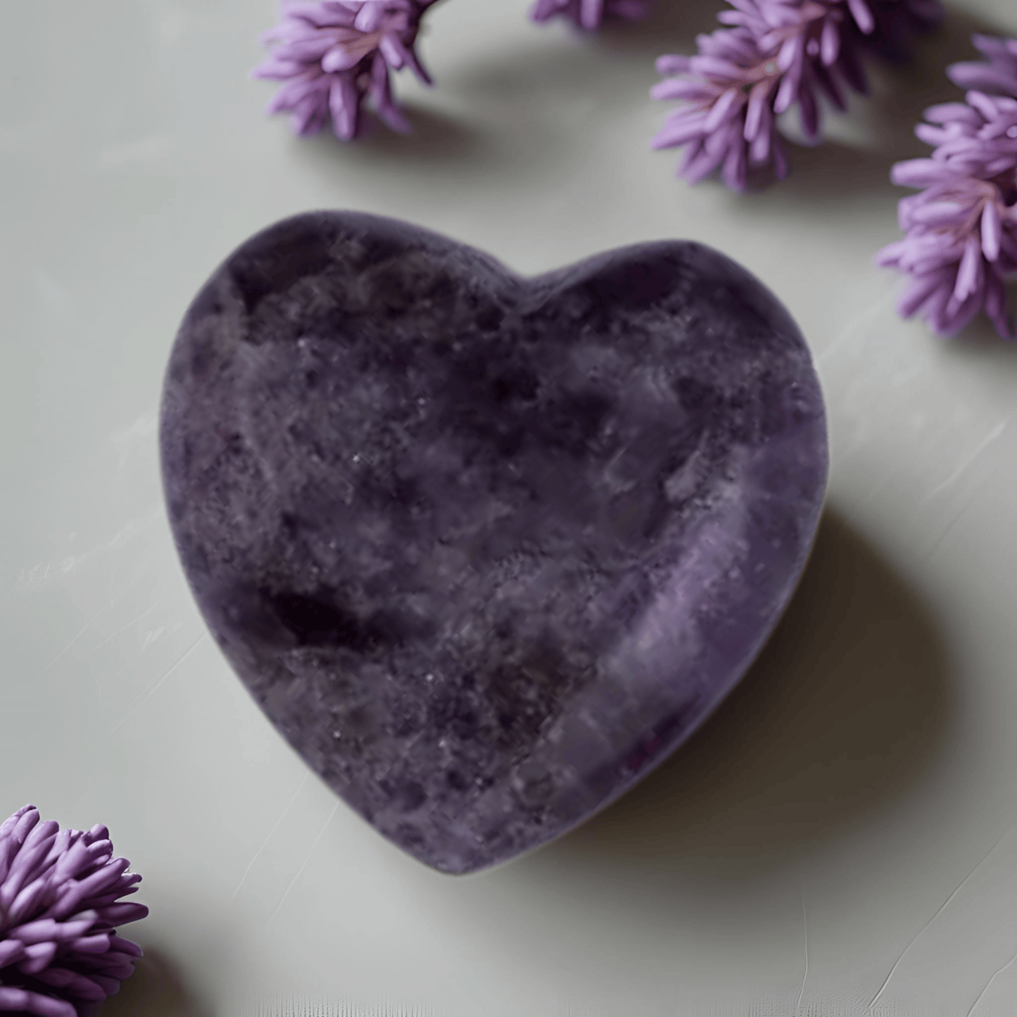 Heart-shaped purple stone with lavender flowers on a light surface