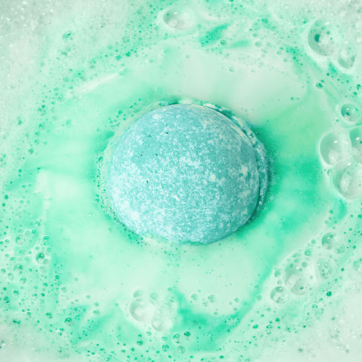 Green bath bomb fizzing in water