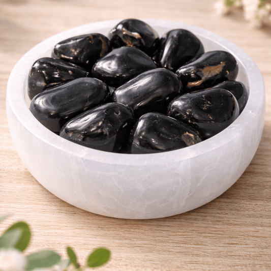 Black stones in a white bowl on a wooden surface