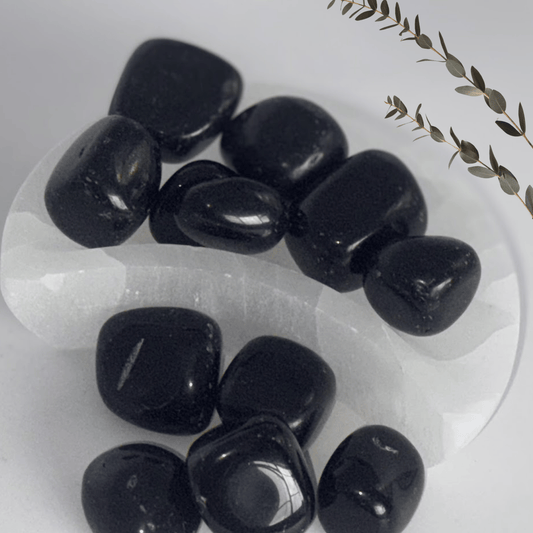 Black Obsidian stones on a selenite Moon Bowl with a minimal background