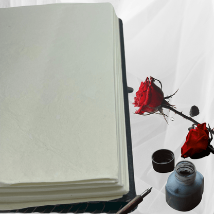 Open notebook with a red rose and inkwell on a white background