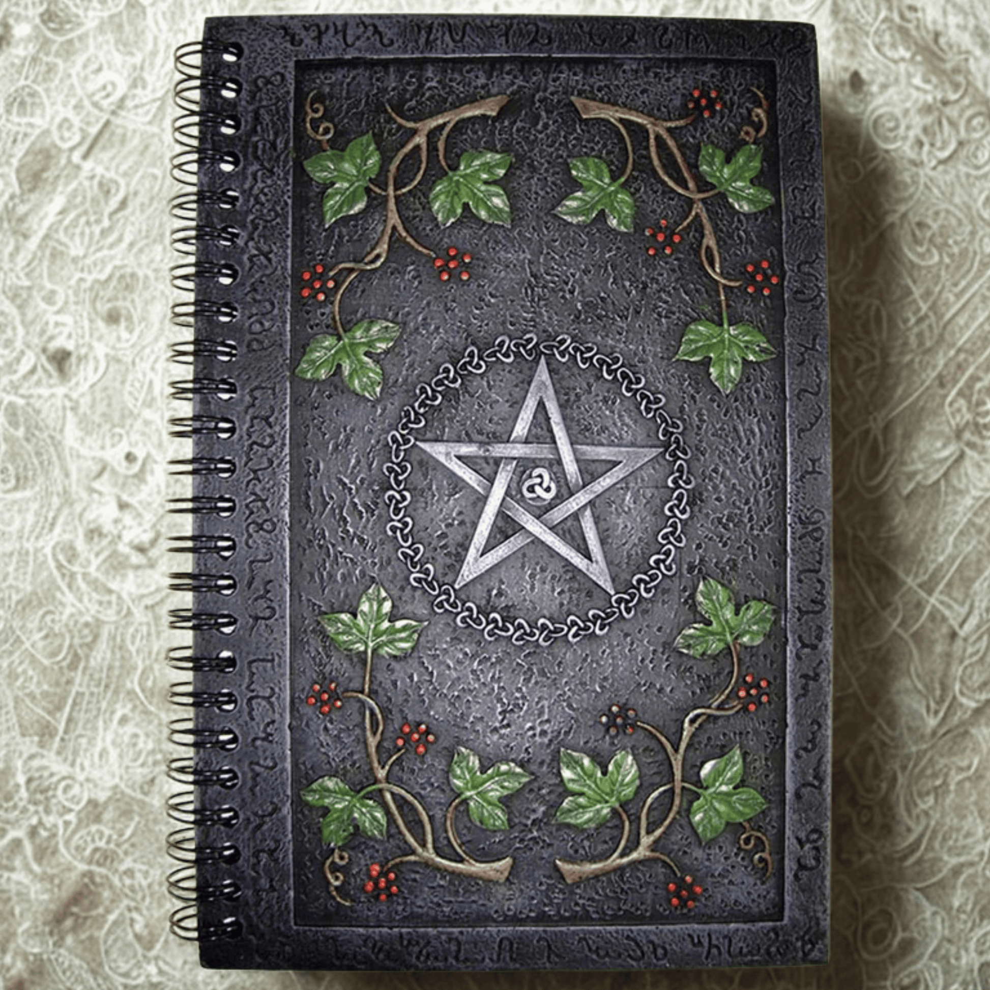 Decorative notebook with pentagram design and leaf patterns on a textured surface