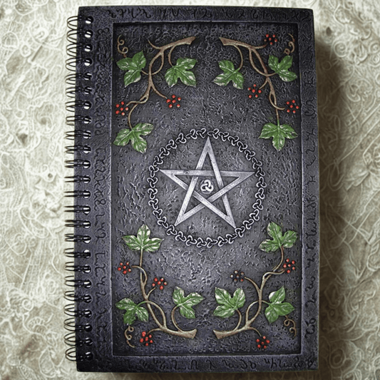 Decorative notebook with pentagram design and leaf patterns on a textured surface