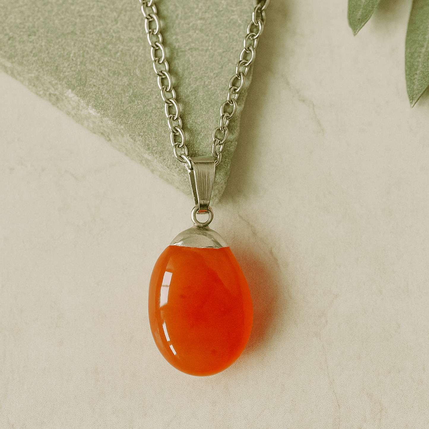 Necklace with a teardrop-shaped orange pendant on a light background