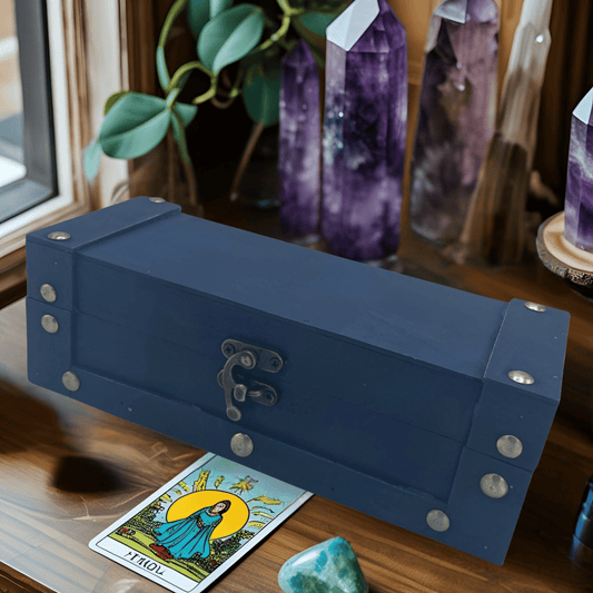 Vintage teal storage box with metal studs and lock sitting on a brown table with a tarot card and crystals in the background