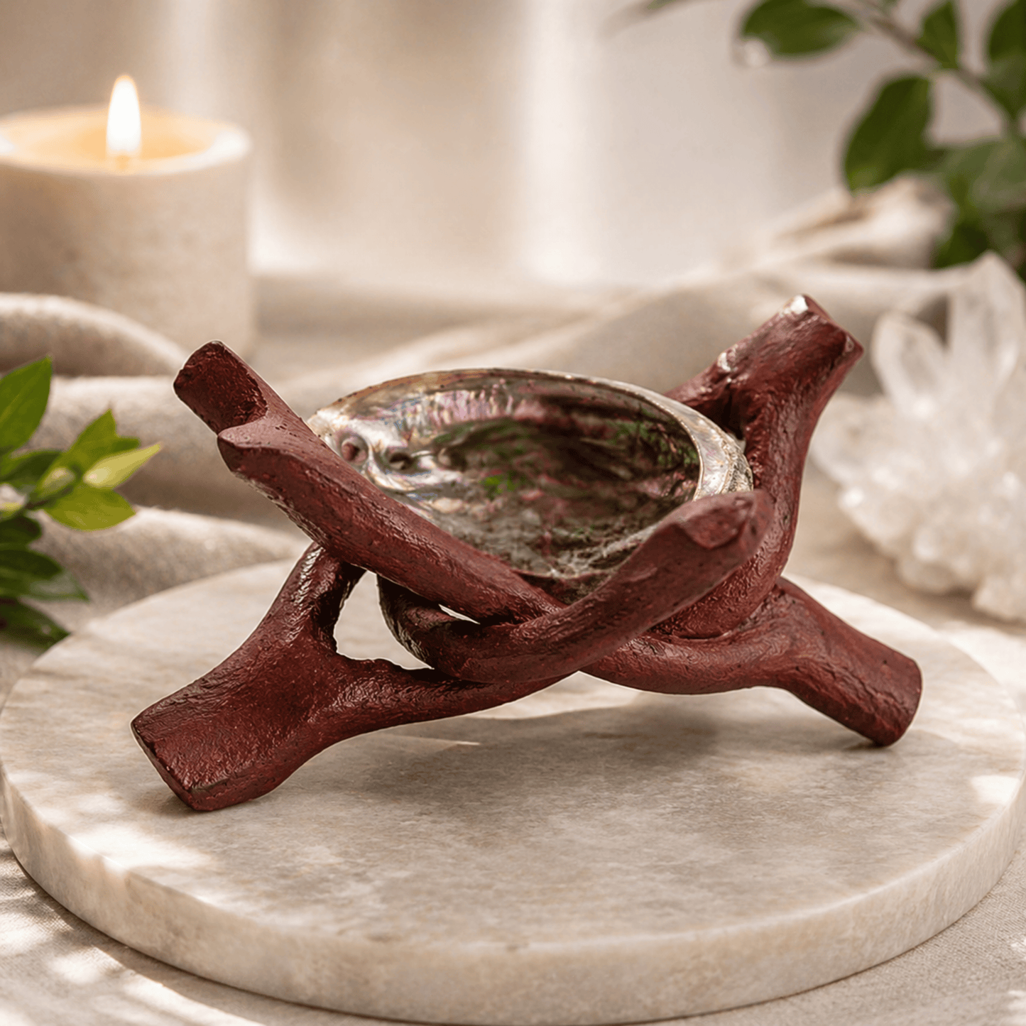 Decorative candle, abalone shell, crystal ball holder shaped like a branch on a marble surface with a blurred background