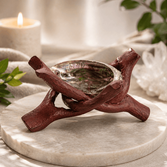 Decorative candle, abalone shell, crystal ball holder shaped like a branch on a marble surface with a blurred background