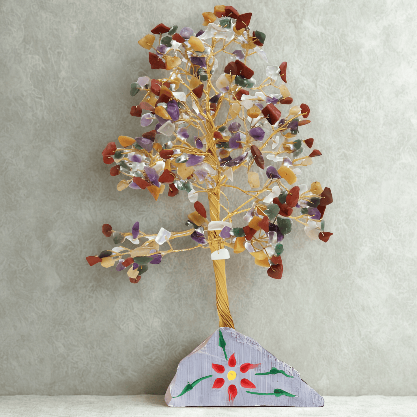 Decorative tree sculpture with multicolored stones on a textured gray background