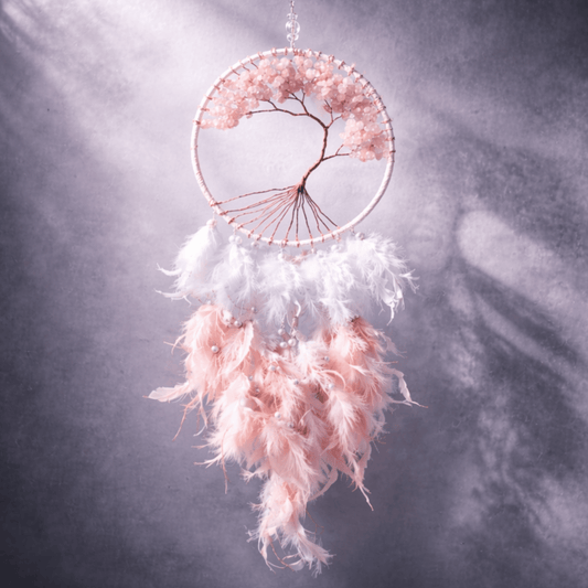 Pink and white dreamcatcher with feathers against a dark background