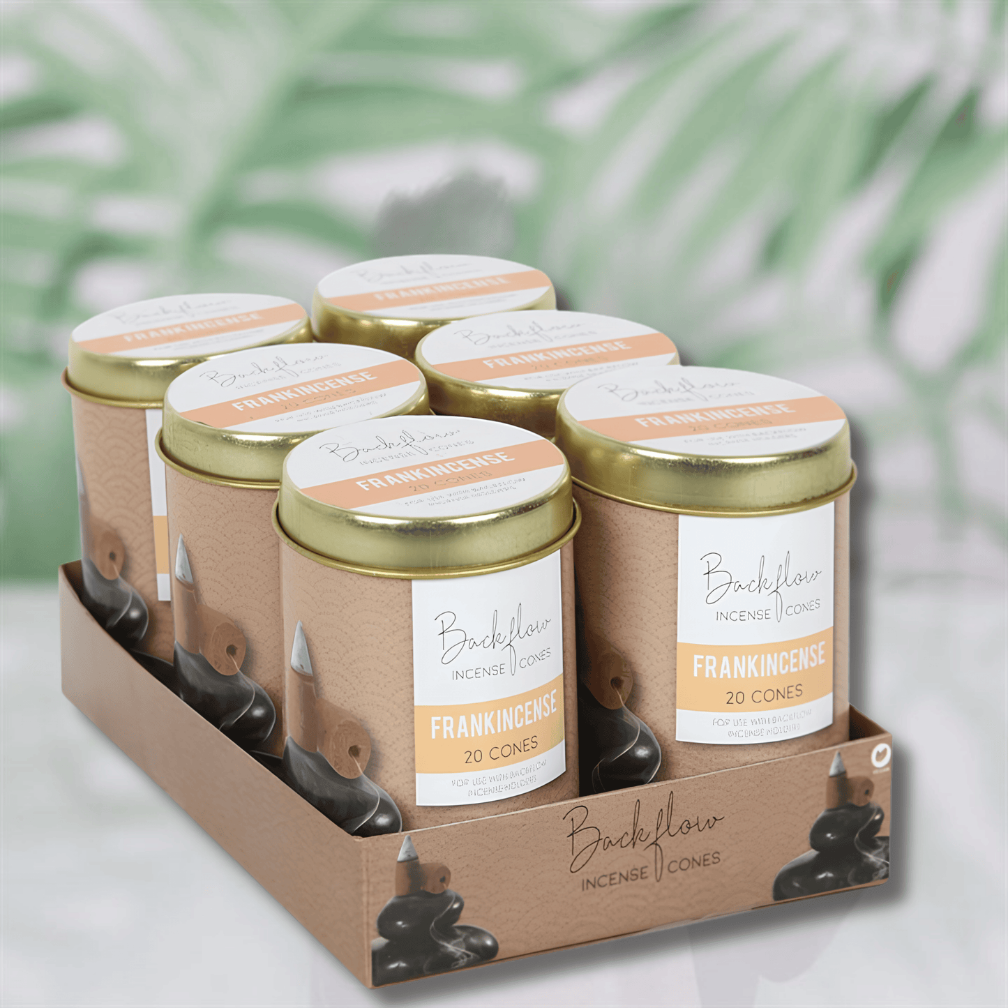 Six Backflow Incense Cones in a cardboard tray display, featuring Frankincense scent with gold lids and labels, set against a soft-focus green leaf background.