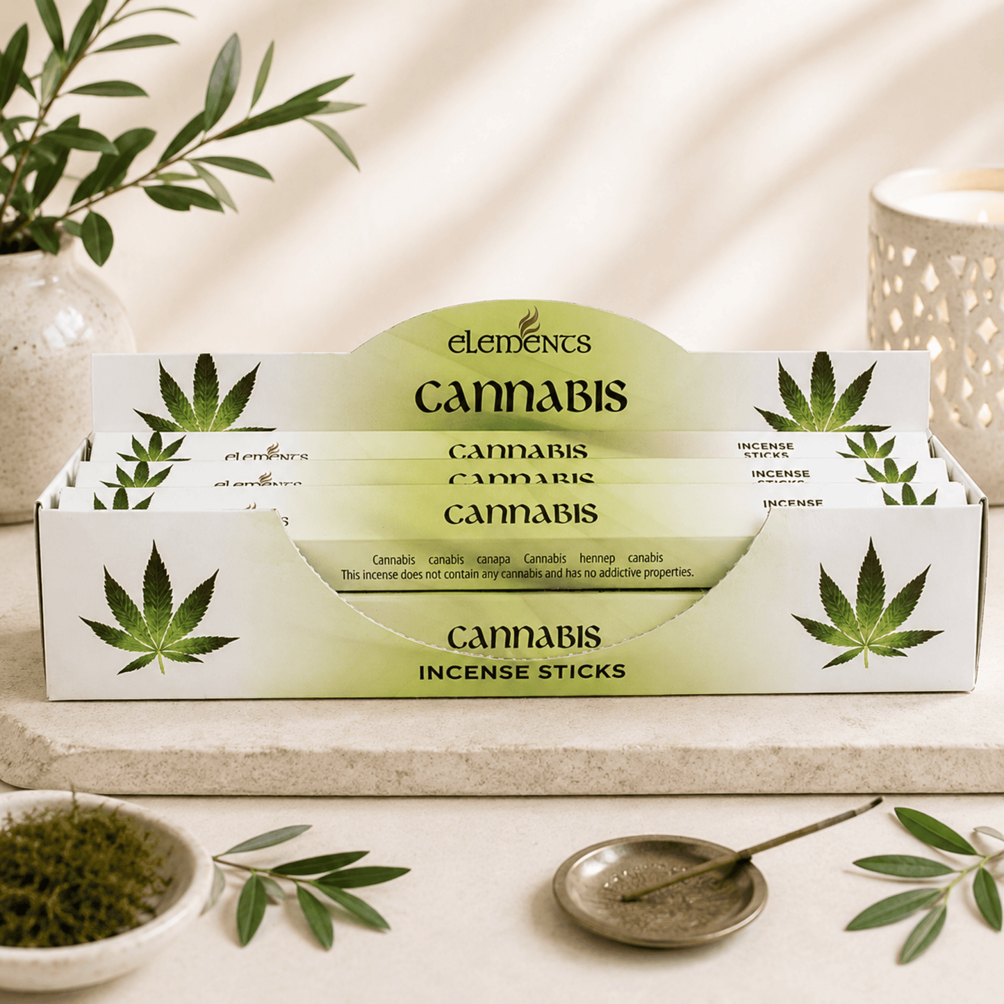 Box of Elements Cannabis incense sticks with green leaves on a neutral background
