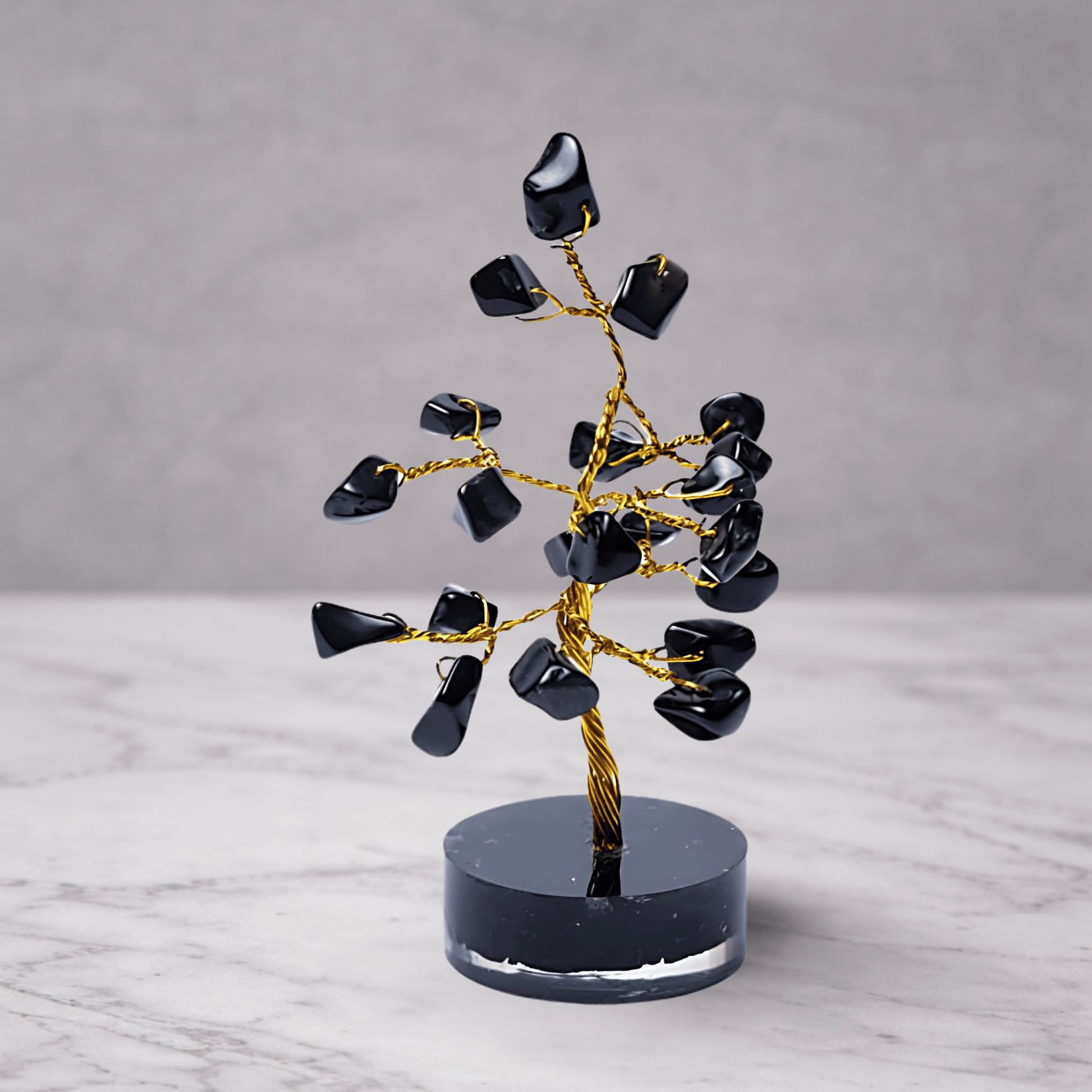 Black agate crystal gemstone tree with dark polished stones on a decorative base, used for grounding, protection and calming feng shui home decor