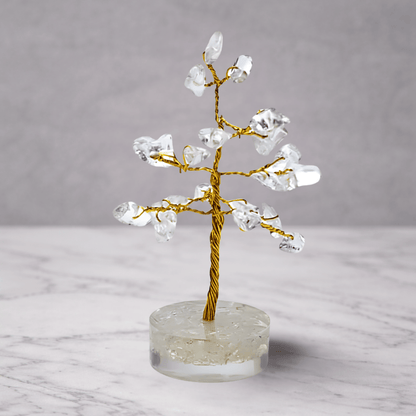 Crystal tree on a clear base with a gold trunk against a gray background