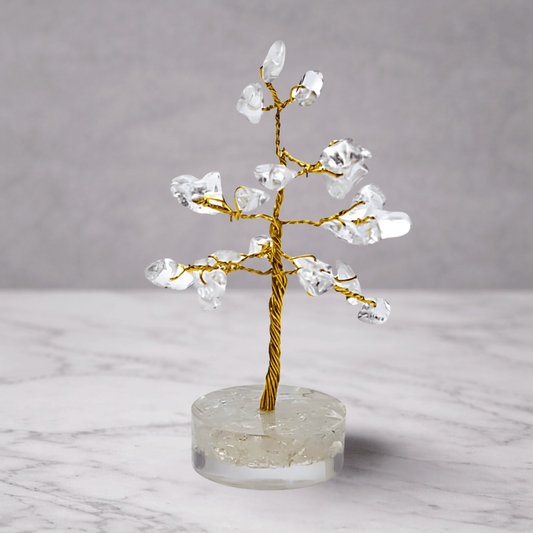 Crystal tree on a clear base with a gold trunk against a gray background