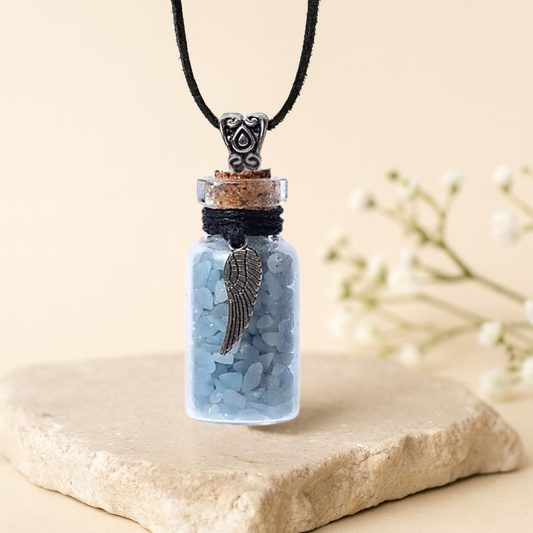 Necklace with a small bottle pendant containing a feather on a beige background