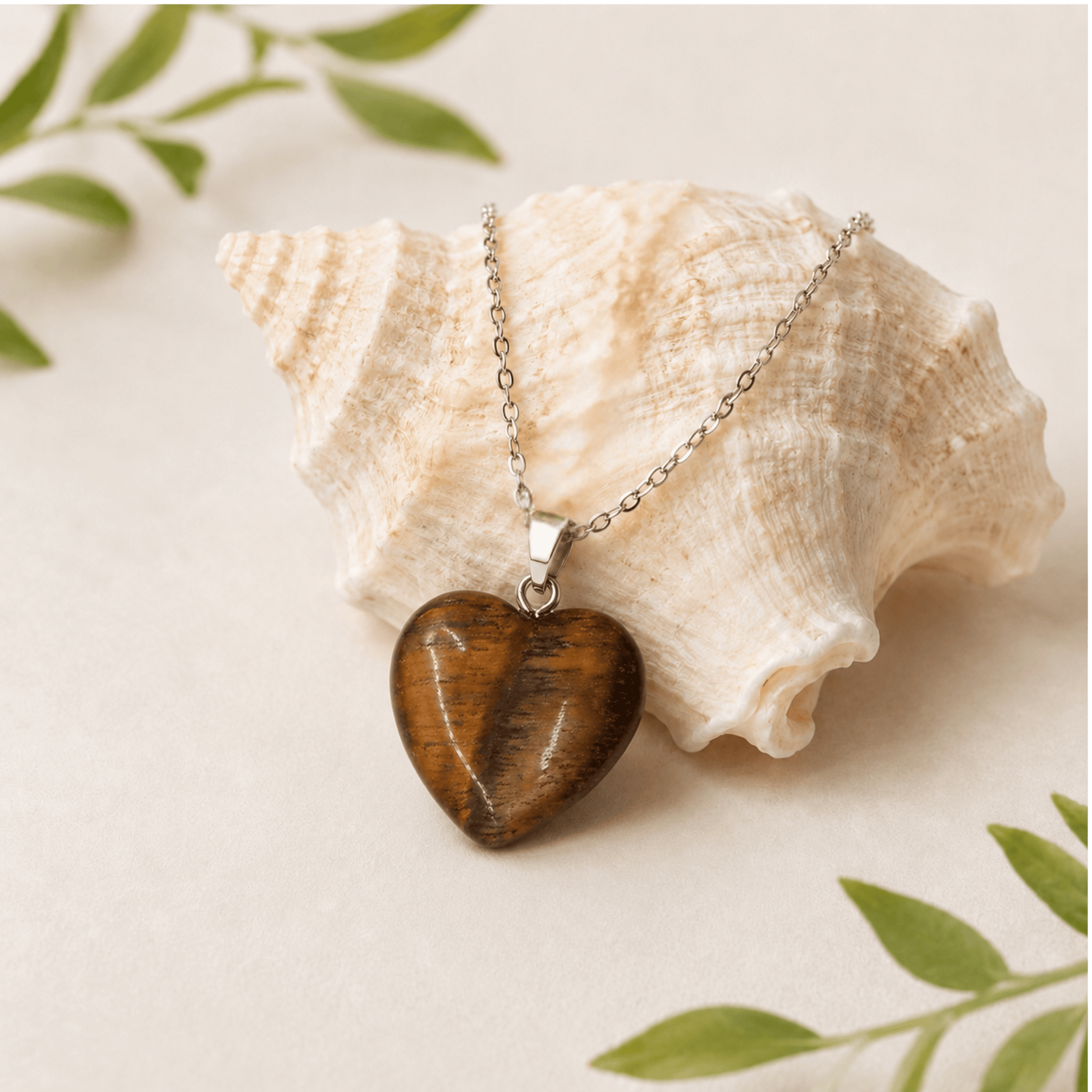 Heart-shaped pendant necklace on a shell with green leaves in the background