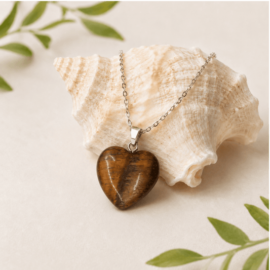 Heart-shaped pendant necklace on a shell with green leaves in the background