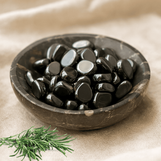 Black Hematite Crystal Tumblestones in a brown ceramic bowl on a beige fabric background