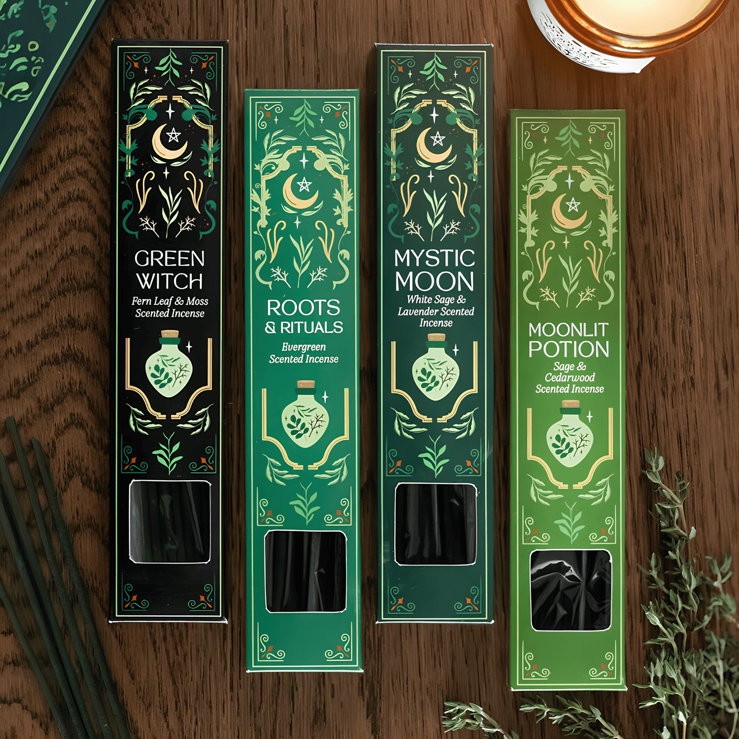 Four tall rectangular scented incense boxes arranged on a wooden surface, each with ornate green and gold illustrated packaging and visible incense sticks through a window near the bottom. The box labels read Green Witch, Roots & Rituals, Mystic Moon, and Moonlit Potion.