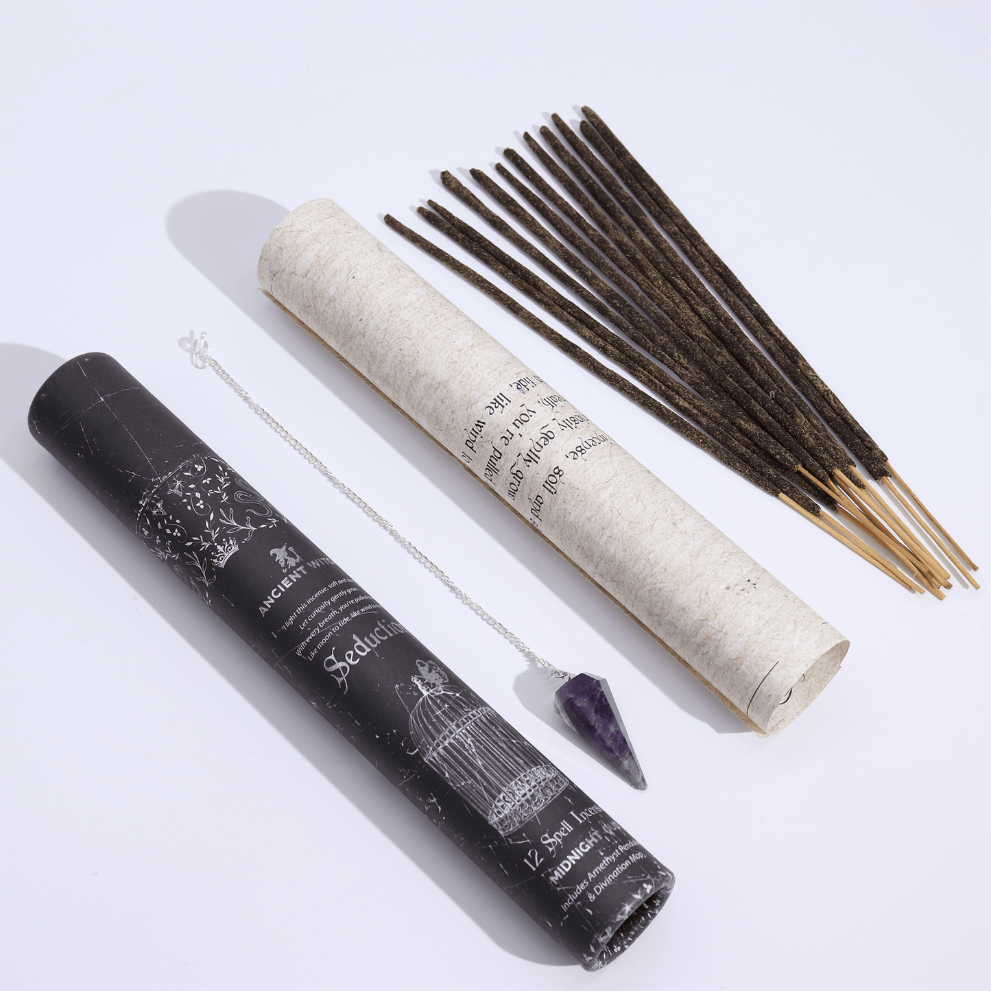 Incense sticks with a roll of incense, pendulum, and amulet on a white background
