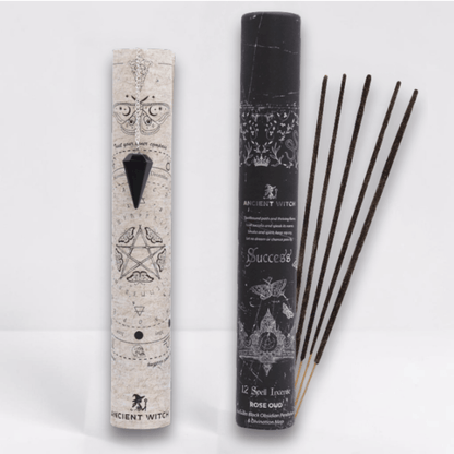 Incense sticks with packaging featuring star and pentacle designs on a white background and a black pointed crystal attached to a silver chain draped over a paper map.