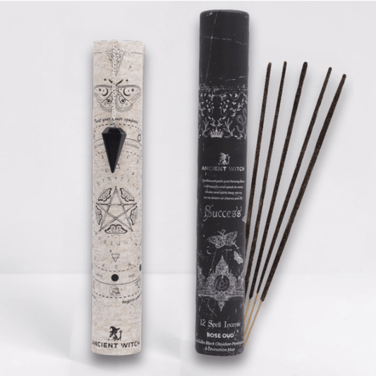 Incense sticks with packaging featuring star and pentacle designs on a white background and a black pointed crystal attached to a silver chain draped over a paper map.