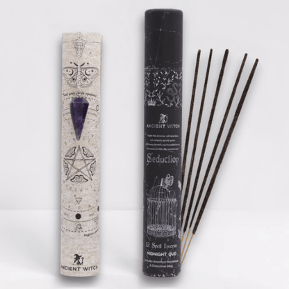 Incense sticks with packaging featuring mystical symbols on a white background. A purple pointed crystal with silver chain attached to it dangled over the divination map.
