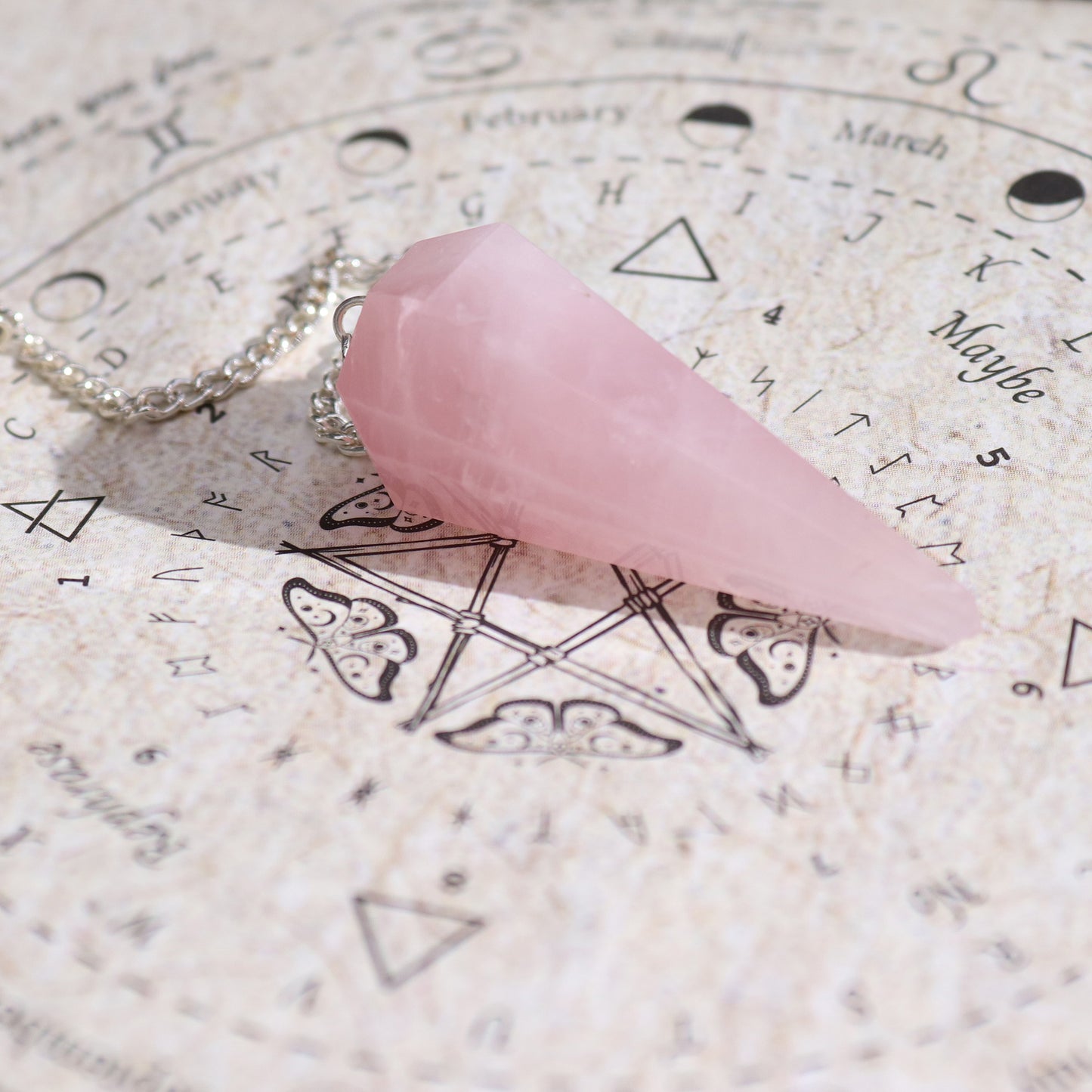 Pink rose quartz crystal on an astrological chart with symbols and text.