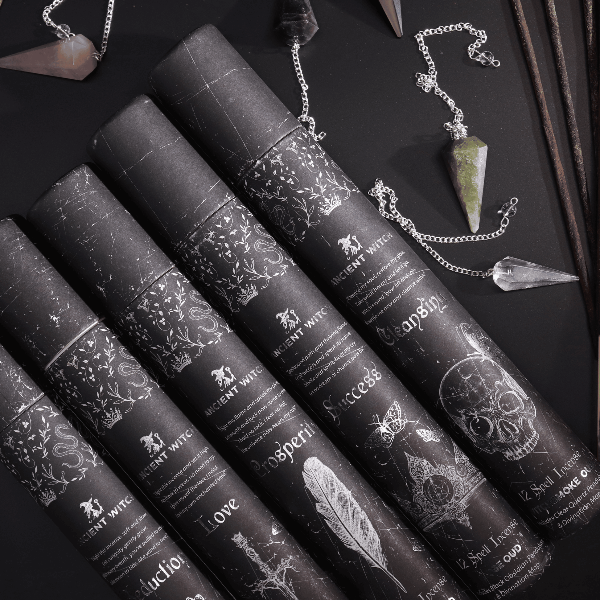 Black cylindrical containers with decorative labels on a dark surface with crystals and jewelry.