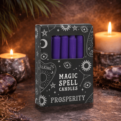 Box of purple spell candles labeled 'Prosperity' with candles and crystals in the background.