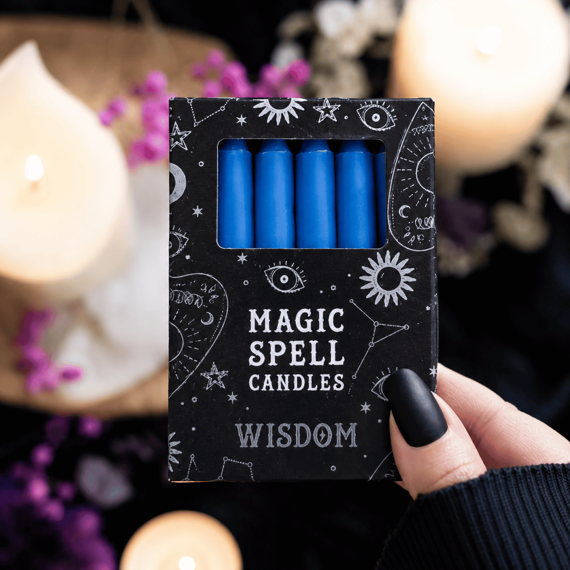 Pack of blue candles labeled 'Magic Spell Candles Wisdom' held by a hand with black nail polish.
