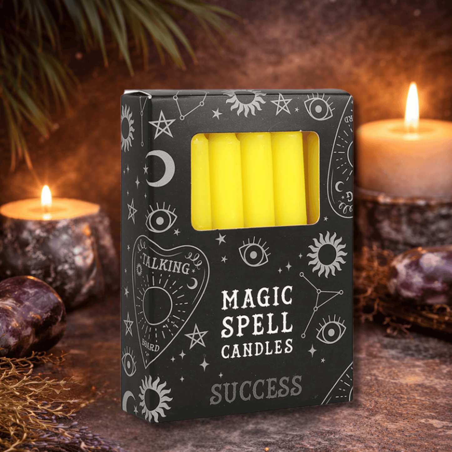 Box of 'Magic Spell Candles' with yellow candles inside, surrounded by candles and crystals on a dark background.