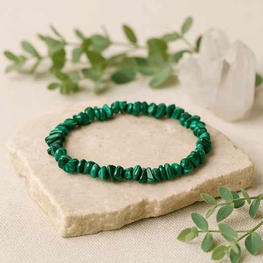 Green beaded bracelet on a stone surface with greenery in the background