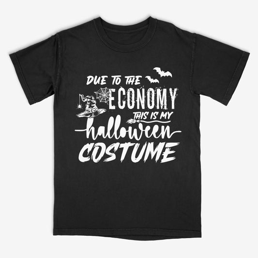 Black t-shirt with Halloween-themed white text "Due to the economy this is my halloween costume"  and graphics of a witches hat and broomstick and bats on a white background
