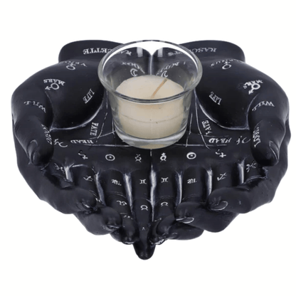 Black resin hands holding a glass with a candle inside, on a white background