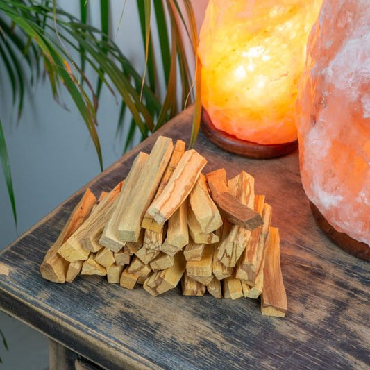 Palo Sticks on a table and salt lamps and plant in the background