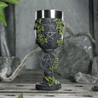 Decorative goblet with pentacle design and greenery on a rustic background